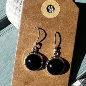 A pair of black earrings hanging on top of a card.