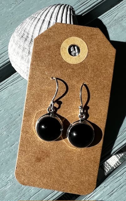 A pair of black earrings hanging on top of a card.