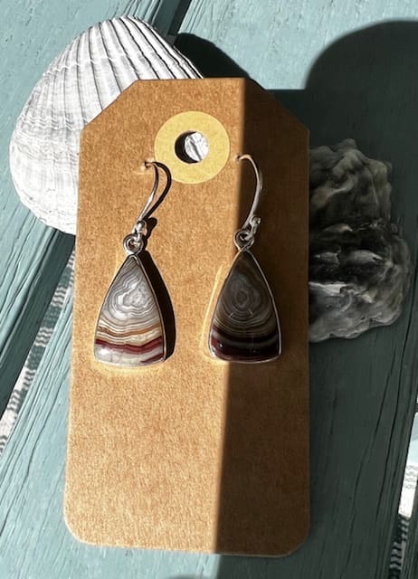 A pair of earrings hanging on top of a wooden box.