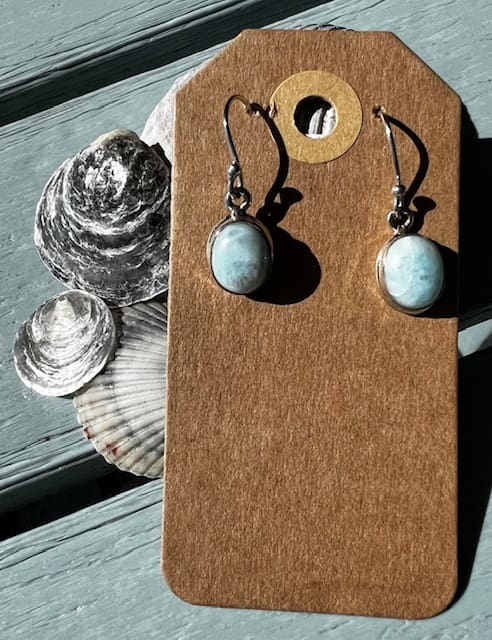 A pair of earrings sitting on top of a wooden board.