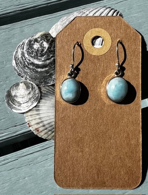 A pair of earrings sitting on top of a wooden board.