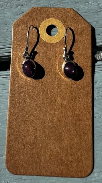 A pair of earrings hanging on a wooden board.