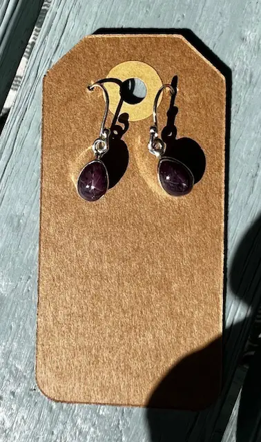 A pair of earrings hanging on a brown card.