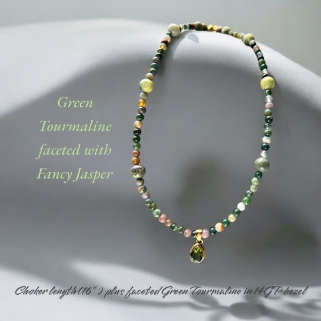 A necklace with fancy jasper beads and a gold charm.