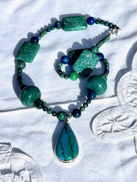 A necklace with green beads and a blue stone.